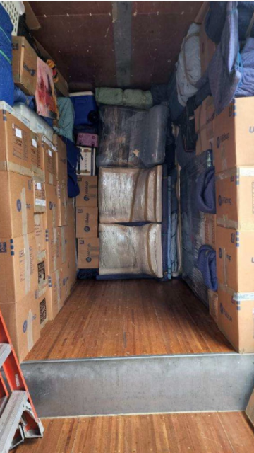 Organized moving truck with blue blankets and labeled boxes