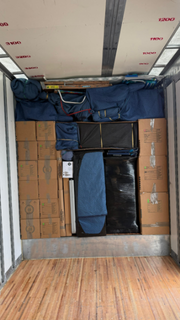 Organized moving truck with blue blankets and labeled boxes